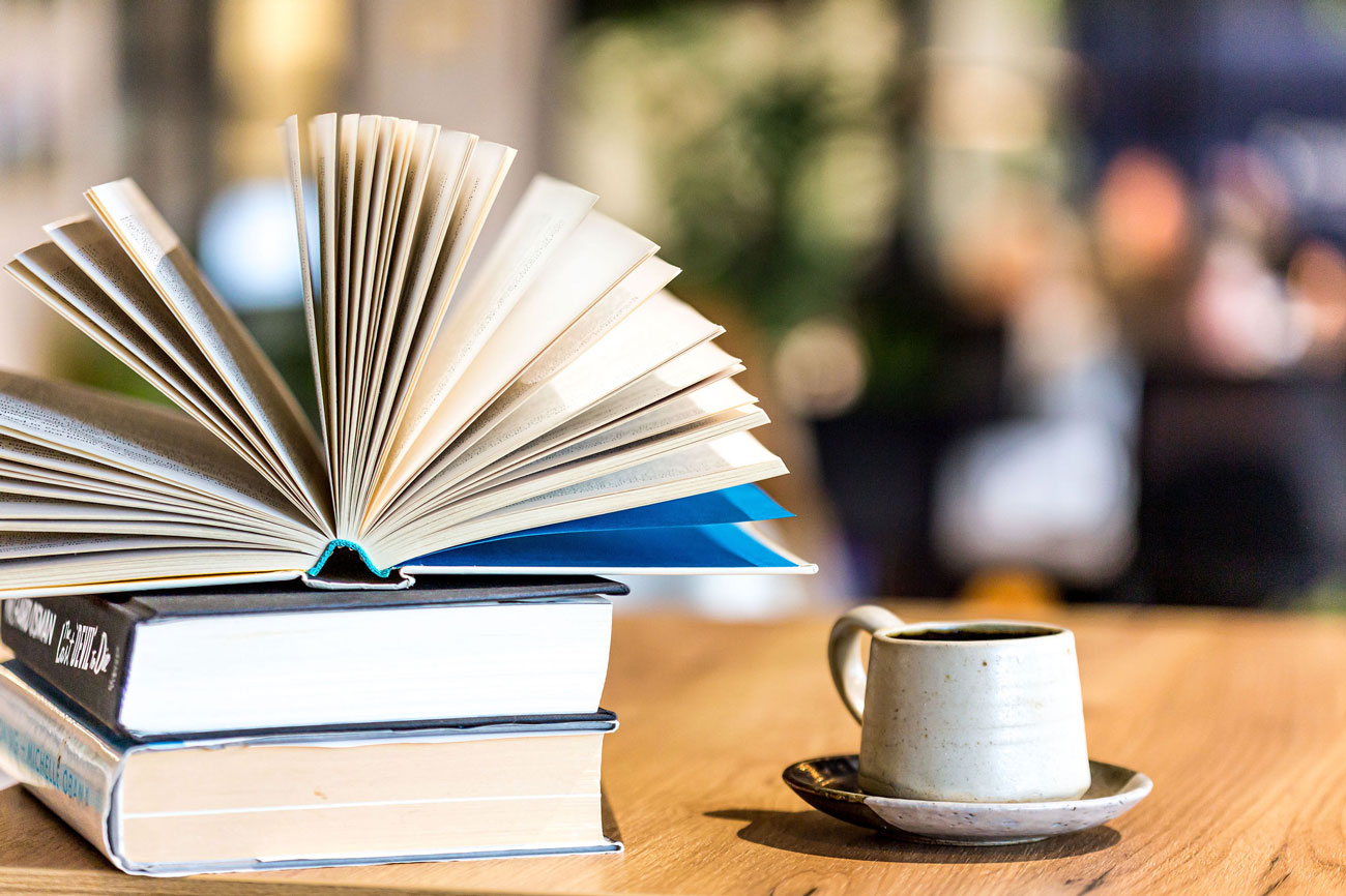 Open book on table with coffee cup next to it - QS Dyslexia Tests