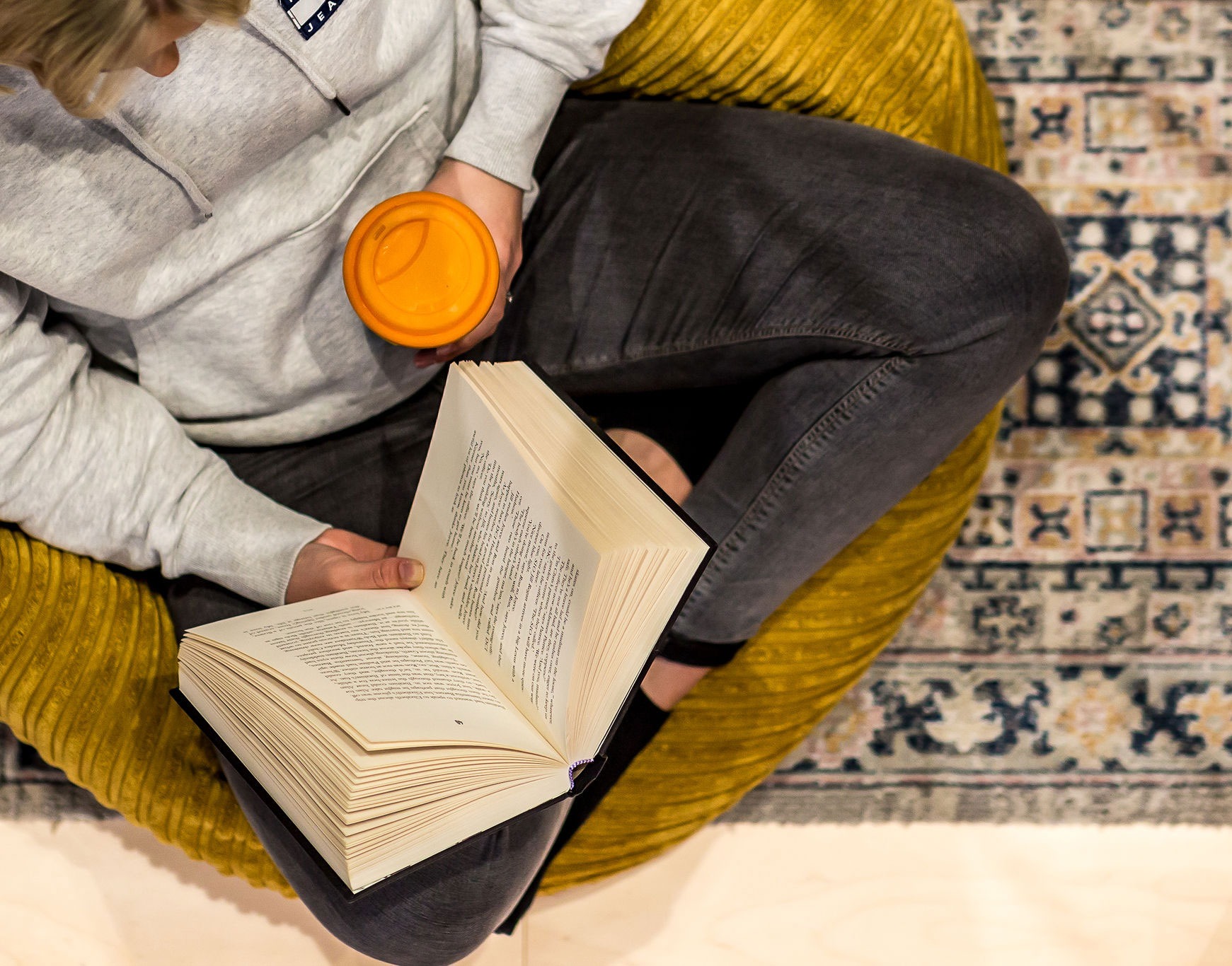 Person sitting on a bean bag reading and drinking coffee - QS Dyslexia Tests